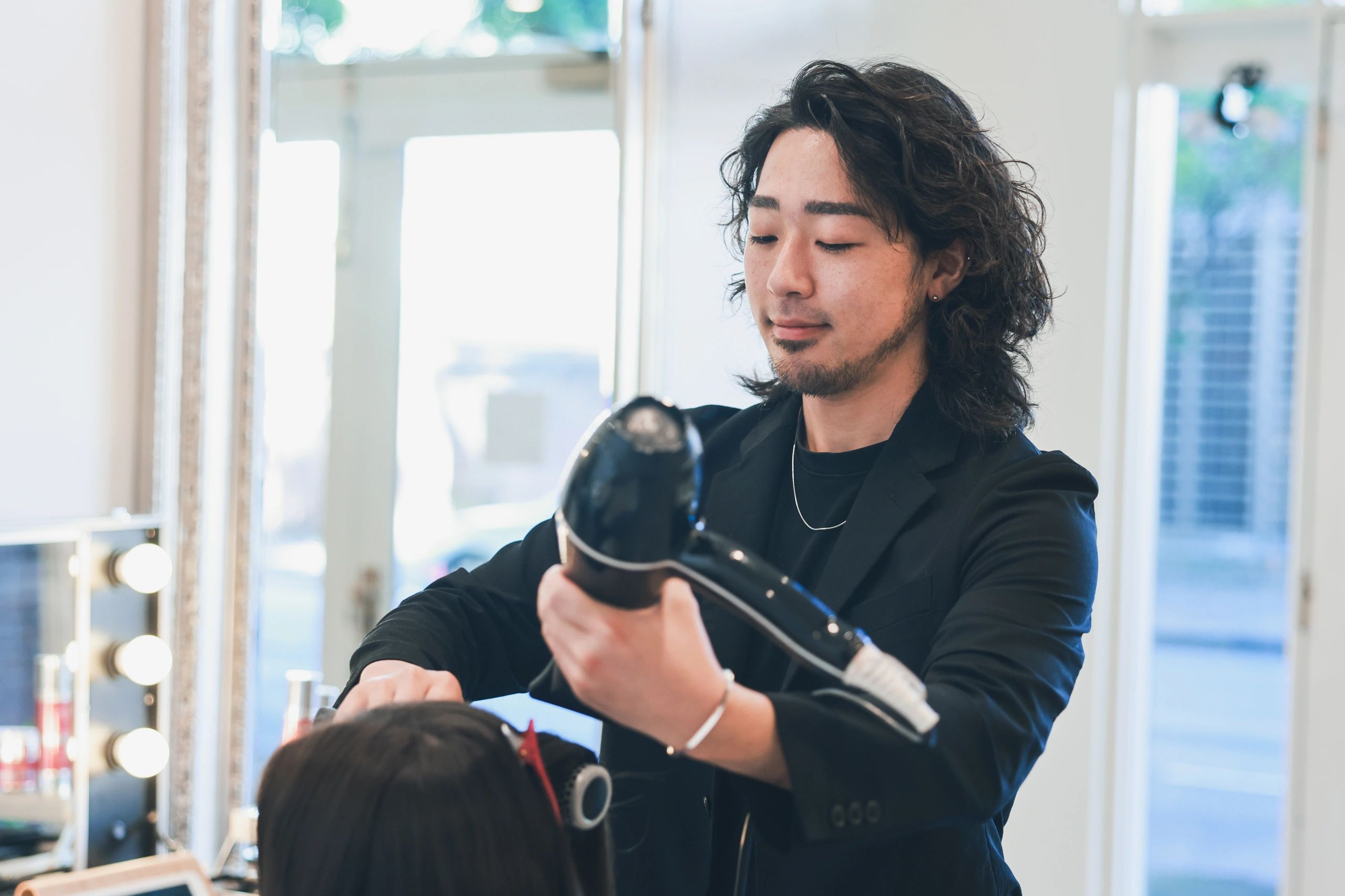 Hair stylist blow drying a client's long hair in a professional salon