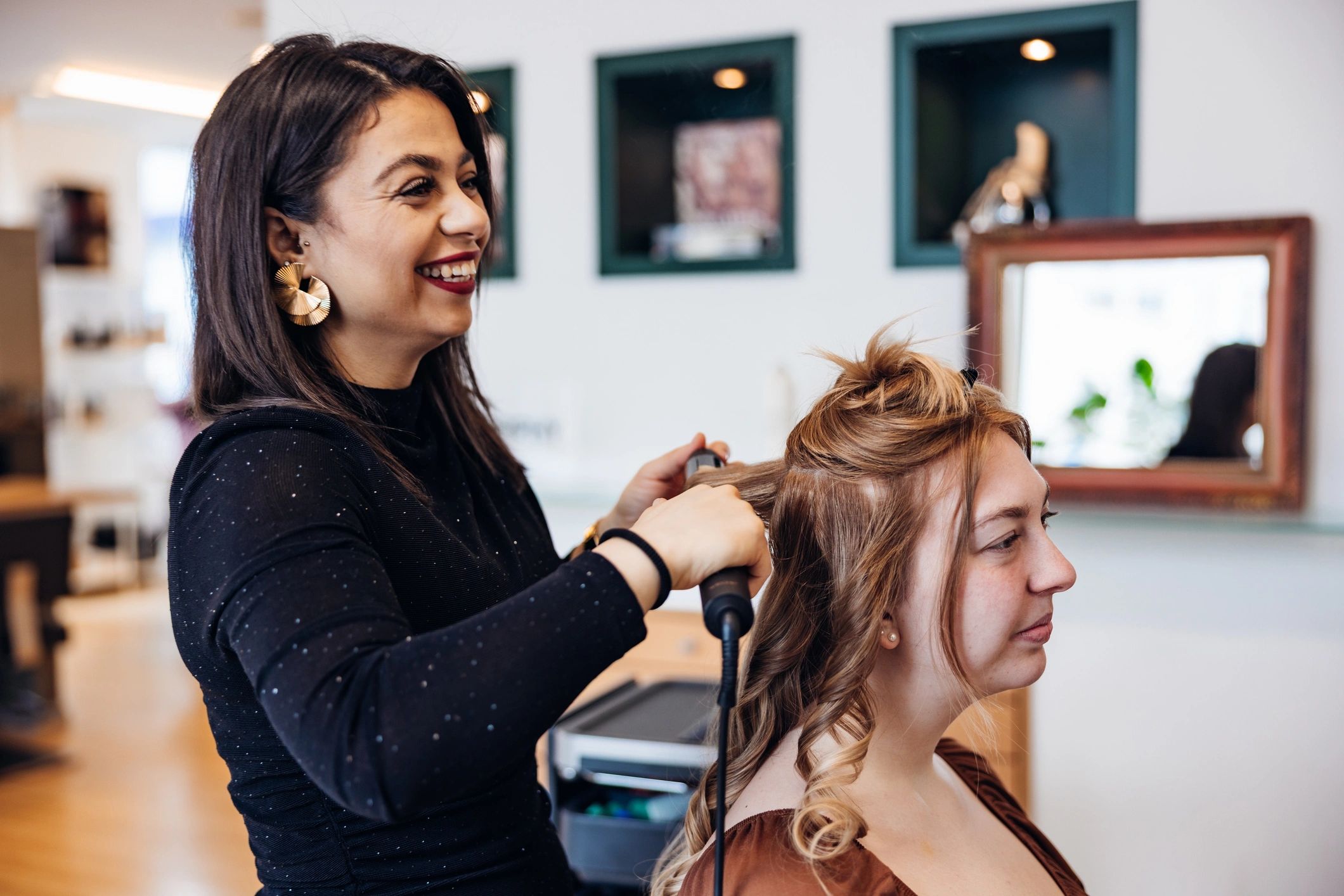 Hair stylist curling a client's hair in a modern salon